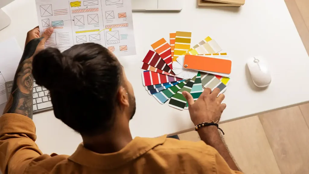 A web designer choosing a color palette while reviewing a website wireframe